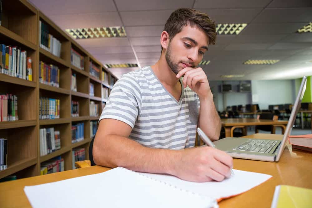 Student studying in the library with laptop at the university