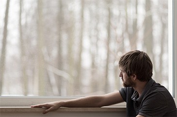 Photo of depressed man looking out the window