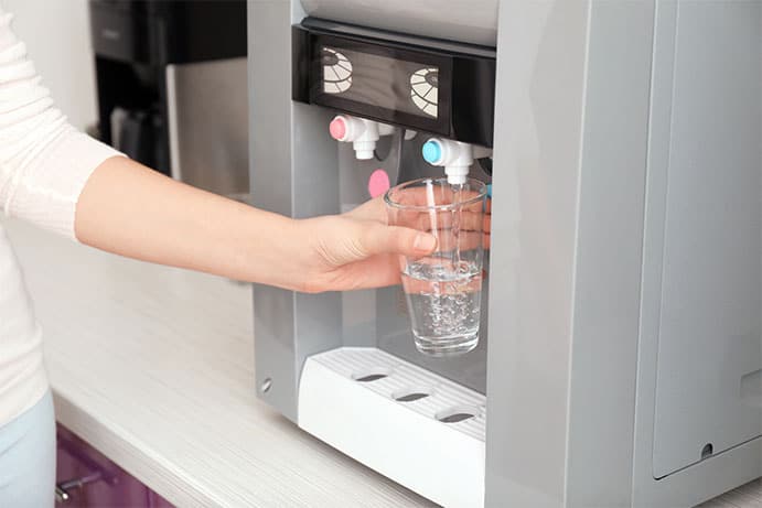 Photo of woman filling up a glass of water.